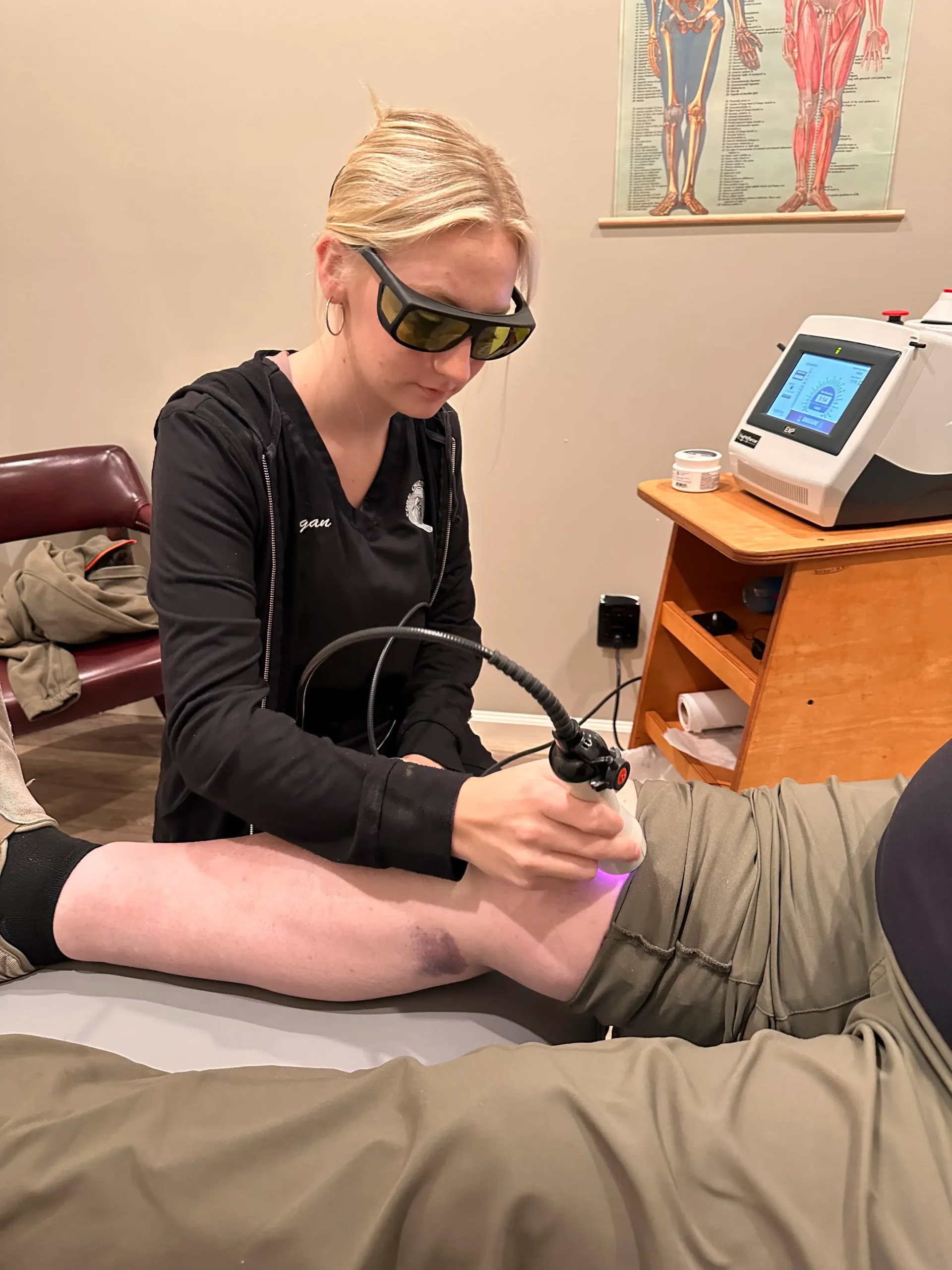 Megan performing laser therapy on a patient's knee