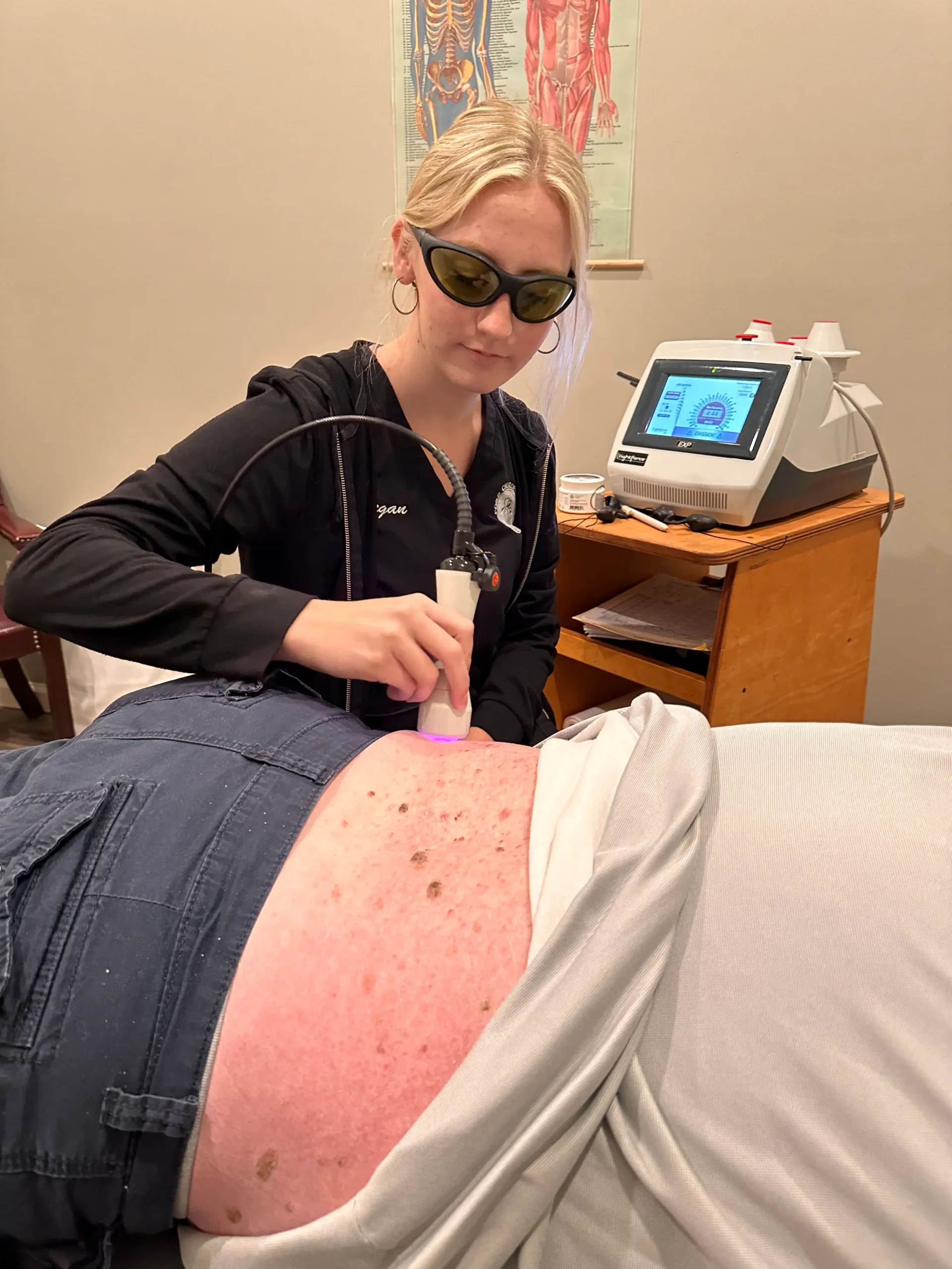 Megan performing laser therapy on a patient's lower back